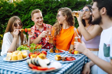 Bir grup genç arkadaş doğada bira eşliğinde piknik yapıyorlar. İnsanlar, yaşam tarzı, rahatlama ve tatil kavramı.
