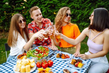 Bir grup genç arkadaş doğada bira eşliğinde piknik yapıyorlar. İnsanlar, yaşam tarzı, rahatlama ve tatil kavramı.