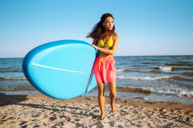 Plajda salgı bezleri olan genç bir kadın. Aktif yaşam tarzı ve sörf kavramı. Yemek bordası.
