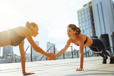 Spor kıyafetli iki genç kadın sabahları dışarıda egzersiz yapıyor. Spor, aktif yaşam, spor eğitimi, sağlıklı yaşam tarzı..