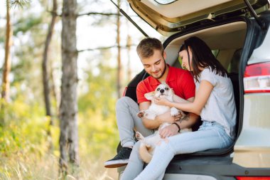 Seyahat ederken köpeğiyle birlikte arabasının arka koltuğunda sevgi dolu ve sevgi dolu bir çiftin portresi. Aktif yaşam tarzı, seyahat, aşk ve tatil kavramı. Evcil hayvan ve insan.