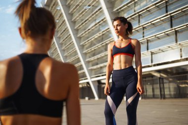 Spor kıyafetli iki genç kadın sabahları dışarıda egzersiz yapıyor. Spor, aktif yaşam, spor eğitimi, sağlıklı yaşam tarzı..