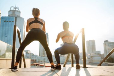 Spor kıyafetli iki genç kadın sabahları dışarıda egzersiz yapıyor. Spor, aktif yaşam, spor eğitimi, sağlıklı yaşam tarzı..