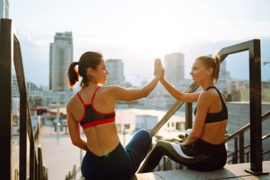 Spor kıyafetli iki genç kadın sabahları dışarıda egzersiz yapıyor. Spor, aktif yaşam, spor eğitimi, sağlıklı yaşam tarzı..