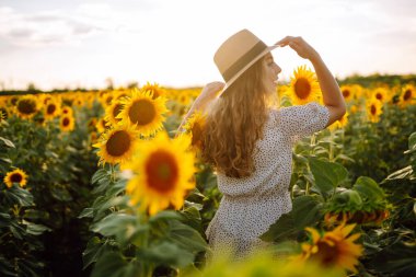 Sarı ayçiçekleriyle çevrili mutlu genç bir kadın. Çiçek bahçesinde, tatilde seyahat ediyor..