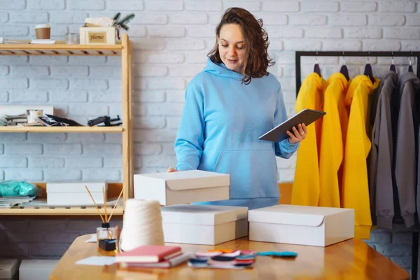 stock image Portrait of female owner of fashion store using digital tablet to check stock on rails in clothing store. Online sales. Shopping concept.