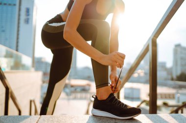 Genç bir kadın spor ayakkabılarını bağlarken dışarıda koşuya hazırlanıyor. Sağlık ve spor konsepti. Etkin yaşam.