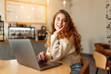 Kafede dizüstü bilgisayarı olan genç bir kadın. İş, blog yazma, serbest yazarlık, eğitim kavramı.