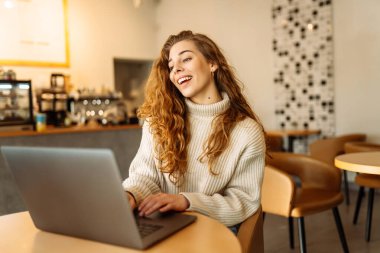Kafede dizüstü bilgisayarı olan genç bir kadın. İş, blog yazma, serbest yazarlık, eğitim kavramı.