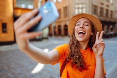 Selfie zamanı. Bir turist sokakta yürürken akıllı telefon kamerasıyla selfie çeker. Yaşam tarzı, seyahat, turizm, aktif yaşam.