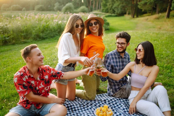 Group of young people gathered in garden for picnic. Friends have fun and  drink beer. Vacation, picnic, friendship or holliday concept.