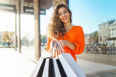 Alışveriş çantalı genç bir kadın güneşli bir cadde boyunca yürüyor. satış, alışveriş, alışveriş, yaşam tarzı konsepti, tüketim.