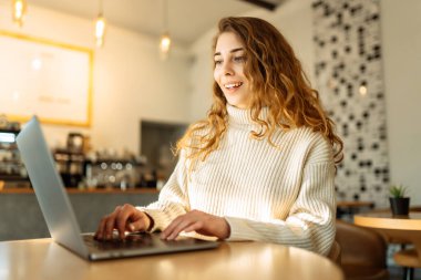 Evde dizüstü bilgisayarı olan genç bir kadın. Serbest çalışma, çevrimiçi kurs, uzaktan çalışma ve yaşam tarzı konsepti. Bilgisayarla online alışveriş