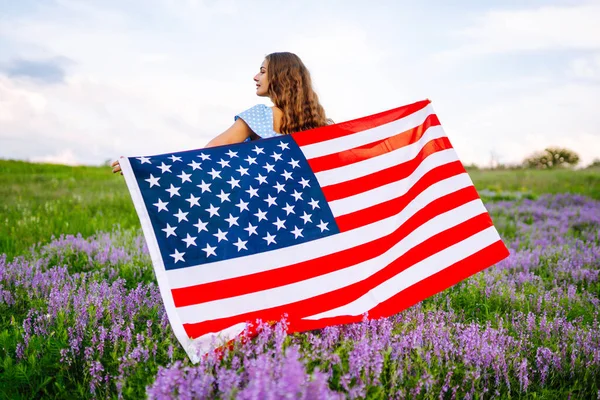 Çiçekli Çayırda Amerikan Bayrağı Taşıyan Genç Bir Kadın Temmuz Bağımsızlık — Stok fotoğraf