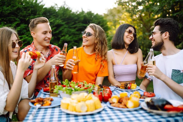 Happy friends in picnic in the park. Friends grill meat, have fun, relax. oncept of lifestyle, holidays, weekends and leisure.