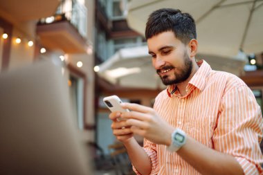 Başarılı genç öğrenci serbest bilgisayar kullanıyor, web siteleri izliyor, uzaktan çalışıyor, e-ticareti sokak kafesinde internetten öğreniyor..