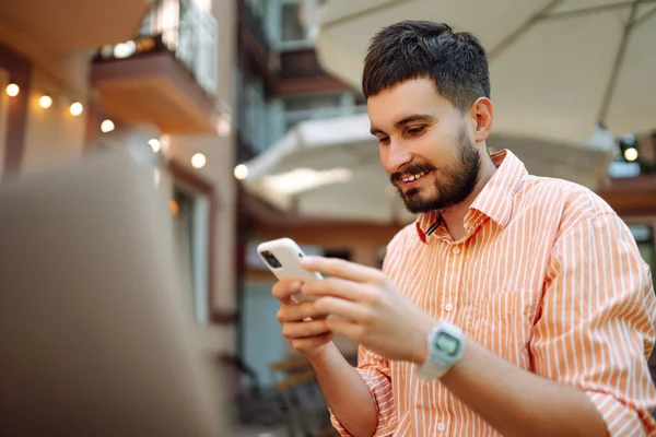 Başarılı genç öğrenci serbest bilgisayar kullanıyor, web siteleri izliyor, uzaktan çalışıyor, e-ticareti sokak kafesinde internetten öğreniyor..