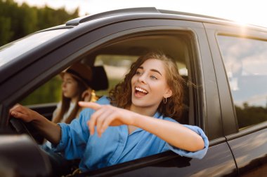 İki genç kadın araba gezisinde eğleniyor. Yaşam tarzı, seyahat, turizm, doğa, aktif yaşam.