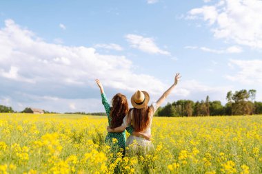 Çiçek açan alanda iki güzel kadın. Doğa, tatil, rahatlama ve yaşam tarzı. Yaz manzarası.