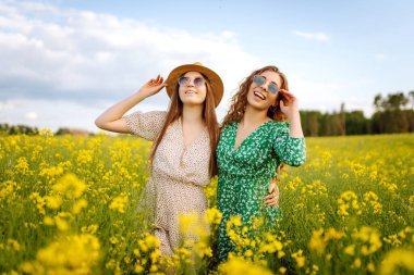 Çiçek açan alanda iki güzel kadın. Doğa, tatil, rahatlama ve yaşam tarzı. Yaz manzarası.