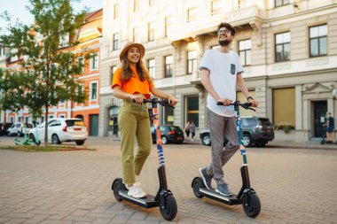 Genç çift şehirde elektrikli scooter sürerken eğleniyor. Aktif hayat. Ekolojik ulaşım kavramı.