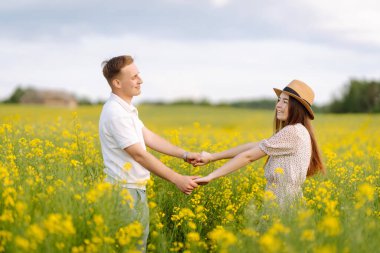 Genç çift çiçek tarlasında. Doğa, tatil, aşk, rahatlama ve yaşam tarzı. Yaz manzarası. 