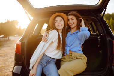 İki genç kadın yolculuk sırasında arabada selfie çekiyor. Yaşam tarzı, seyahat, turizm, doğa, aktif yaşam.
