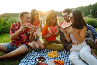 Açık havada piknikte karpuz yiyen gençler. İnsanlar, yaşam tarzı, seyahat, doğa ve tatil kavramı.