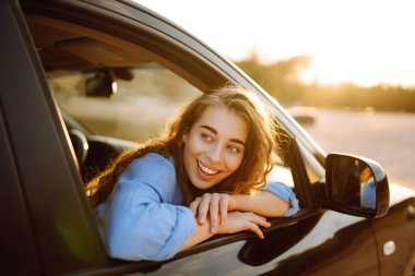 Towards adventure! Young woman is resting and enjoying the trip in the car. Lifestyle, travel, tourism, nature, active life.