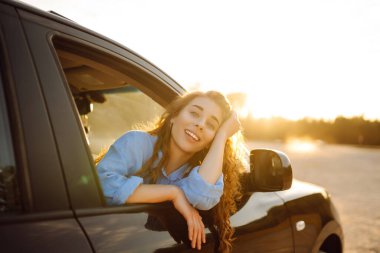 Towards adventure! Young woman is resting and enjoying the trip in the car. Lifestyle, travel, tourism, nature, active life.