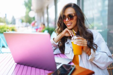 Kafede oturan ve dizüstü bilgisayar kullanan genç bir kadın. Eğitim kavramı, çevrimiçi, serbest, iş.