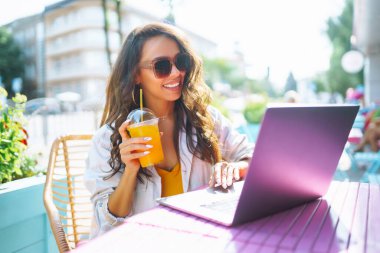 Kafede oturan ve dizüstü bilgisayar kullanan genç bir kadın. Eğitim kavramı, çevrimiçi, serbest, iş.