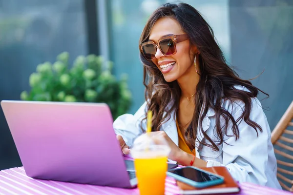 stock image Young woman sitting on the cafe  and using laptop. Concept of education, online, freelance, business.