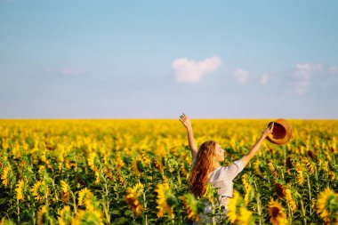 Ayçiçekleriyle tarlada gezinen güzel bir kadın. Moda, yaşam tarzı, seyahat ve tatil kavramı.