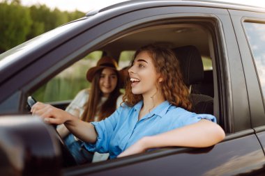 İki genç kadın dinleniyor ve otomobil yolculuğunun tadını çıkarıyor, seyahat, yaşam tarzı konsepti. Araba paylaşımı.