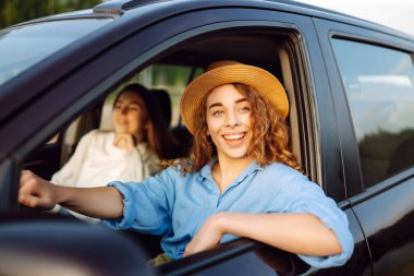 İki genç kadın dinleniyor ve otomobil yolculuğunun tadını çıkarıyor, seyahat, yaşam tarzı konsepti. Araba paylaşımı.