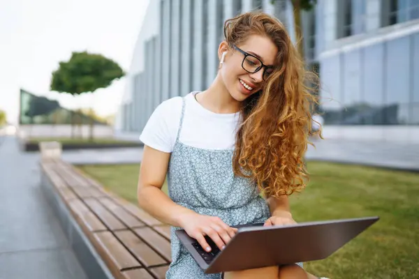Jonge Vrouw Met Een Draadloze Koptelefoon Die Belt Een Laptop — Stockfoto