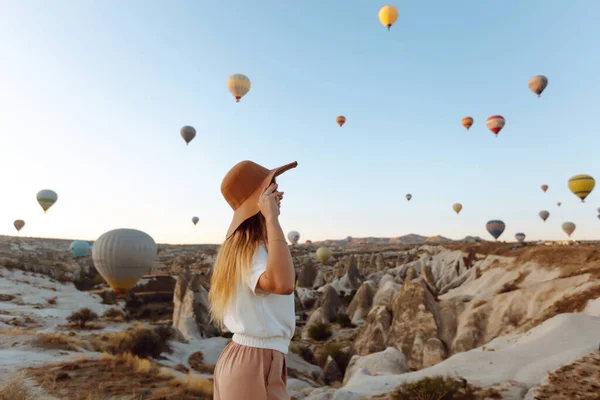 快乐的女人站在山上 背靠着飘扬的气球 土耳其著名旅游区Cappadocia — 图库照片