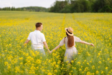 Birbirine aşık genç bir çift kolza tohumu tarlasında yürüyor. Mutlu erkekler ve kadınlar birlikte vakit geçirmenin tadını çıkarıyorlar. Aşk, test, ilişki kavramı.