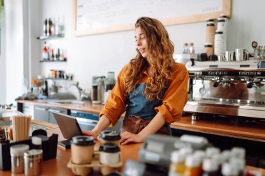 Güzel kadın bir kahve dükkanının arkasında duruyor. Dijital tabletli bir barista sipariş alır. İş konsepti. Paket yemek..