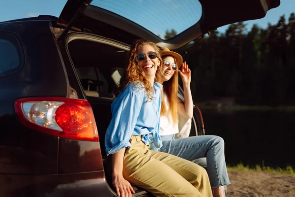 微笑的年轻女子在旅行时坐在汽车后座上玩得很开心 女友们坐在车里 享受着阳光灿烂的天气 自我陶醉 欢笑着 放松着 积极的生活方式 — 图库照片