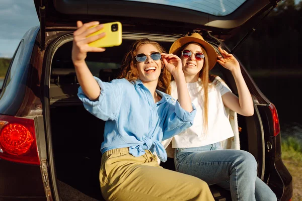 笑顔の若い女性は旅行中に車の後部座席で楽しみを持っています 女の子の友達は 車の中で座って天気を楽しみながら 自撮り リラックスします アクティブなライフスタイル — ストック写真