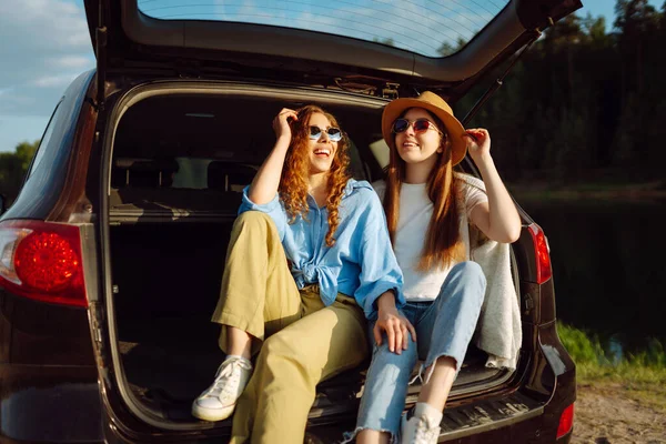 微笑的年轻女子在旅行时坐在汽车后座上玩得很开心 女友们坐在车里 享受着阳光灿烂的天气 自我陶醉 欢笑着 放松着 积极的生活方式 — 图库照片