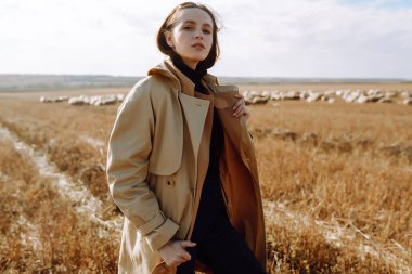 Tarlada poz veren zarif genç bir kadın. Moda, cazibe, yaşam tarzı konsepti. Sonbahar.