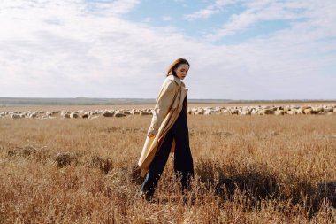 Tarlada poz veren zarif genç bir kadın. Moda, cazibe, yaşam tarzı konsepti. Sonbahar.