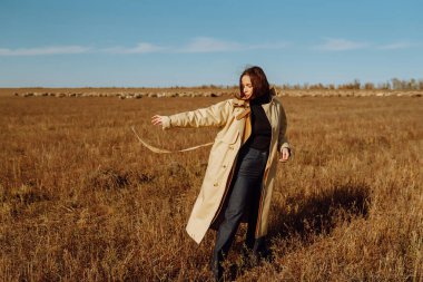 Tarlada poz veren zarif genç bir kadın. Moda, cazibe, yaşam tarzı konsepti. Sonbahar.