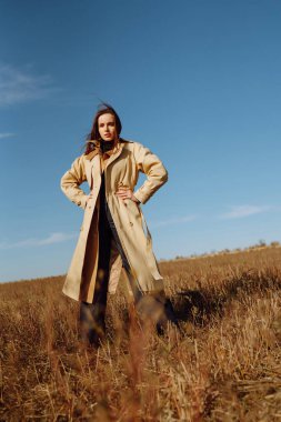 Tarlada poz veren zarif genç bir kadın. Moda, cazibe, yaşam tarzı konsepti. Sonbahar.