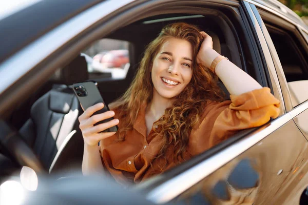 Mulher Feliz Carro Assento Motorista Olha Para Smartphone Uma Jovem — Fotografia de Stock