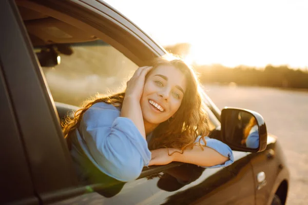 美丽的年轻女子在旅行中欣赏着车窗上的落日 汽车旅行 积极的生活方式概念 日落光 — 图库照片