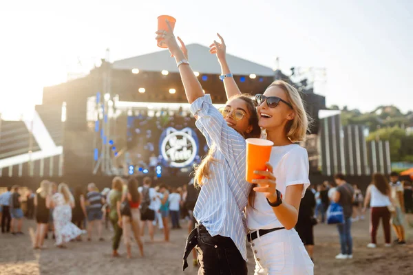 stock image Joyful two young girlfriends have fun with beer at the beach party. Happy two women enjoy the weekend at the music festival. The concept of friendship, holiday, weekend.